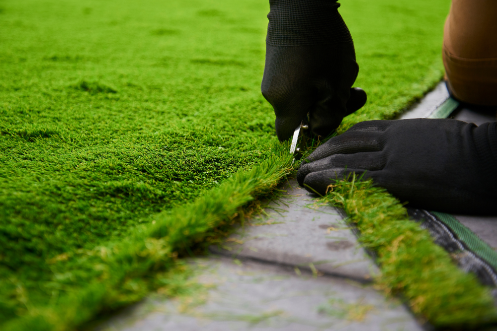 A person is cutting artificial grass with a pair of scissors.