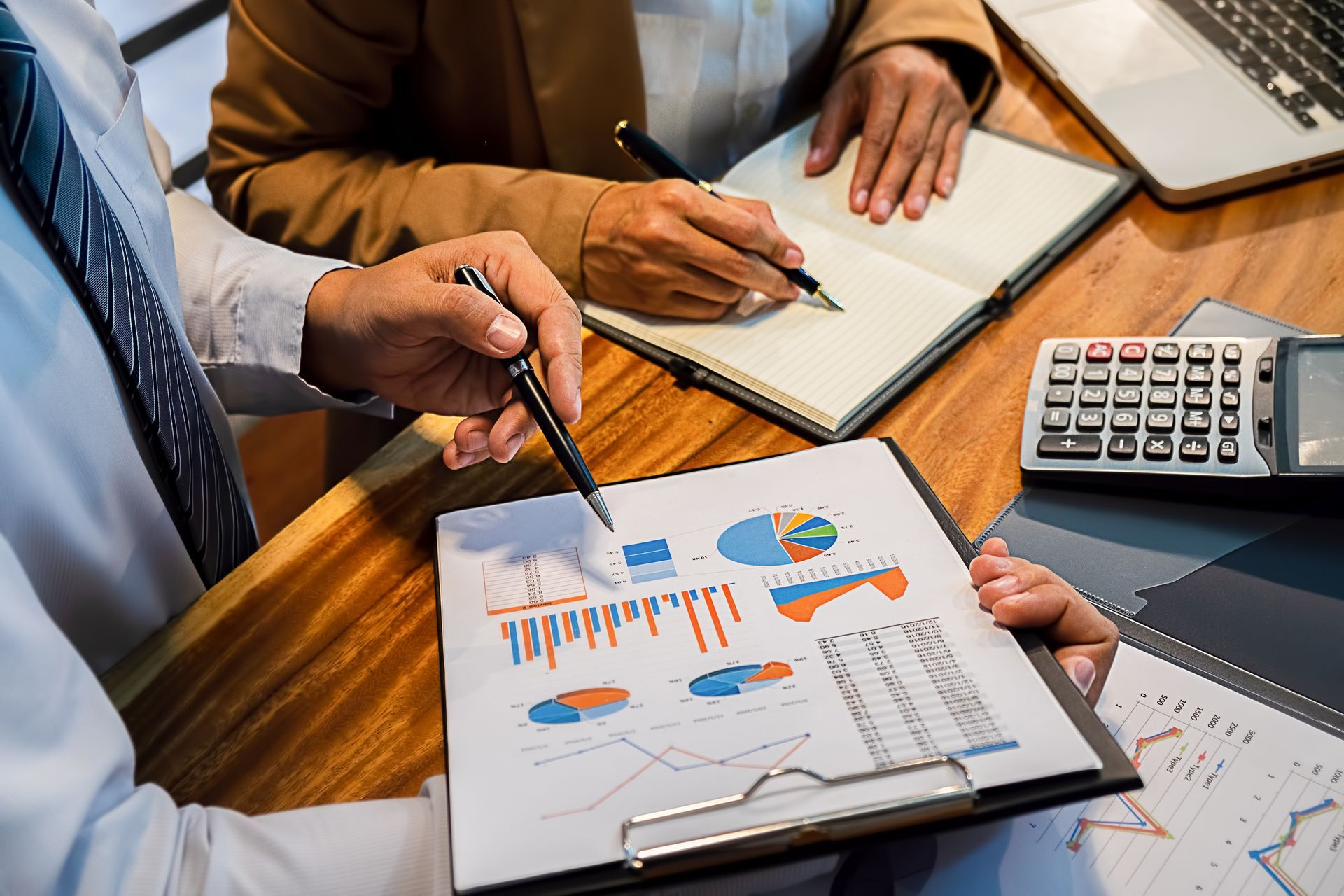Two people reviewing financial charts with a laptop