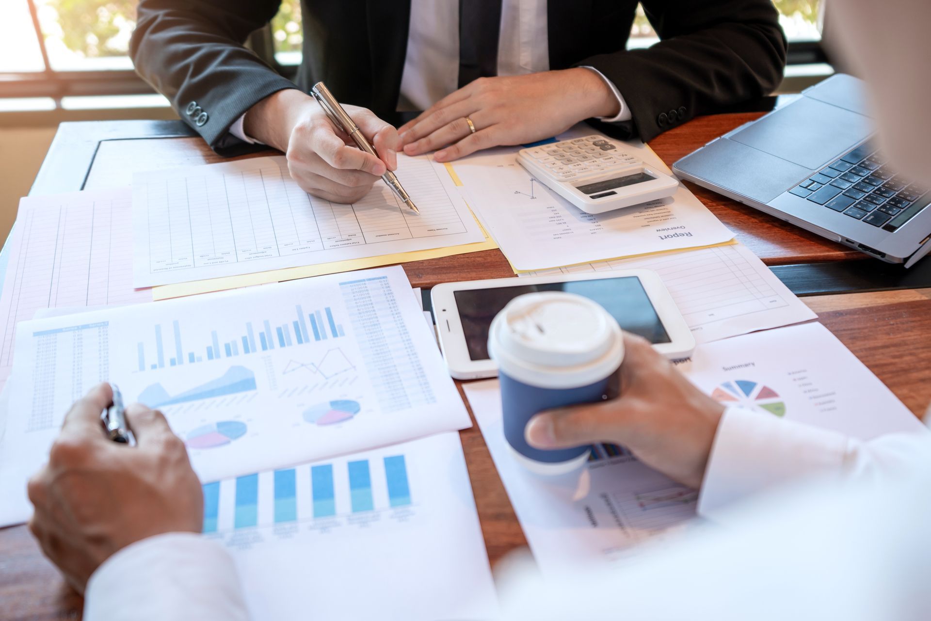 Two people in suits reviewing charts and documents at a table