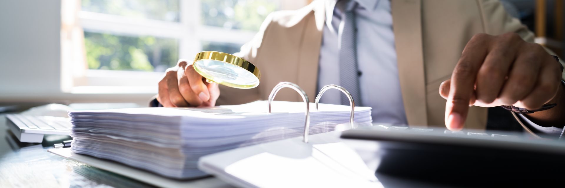 Person examining documents with a magnifying glass