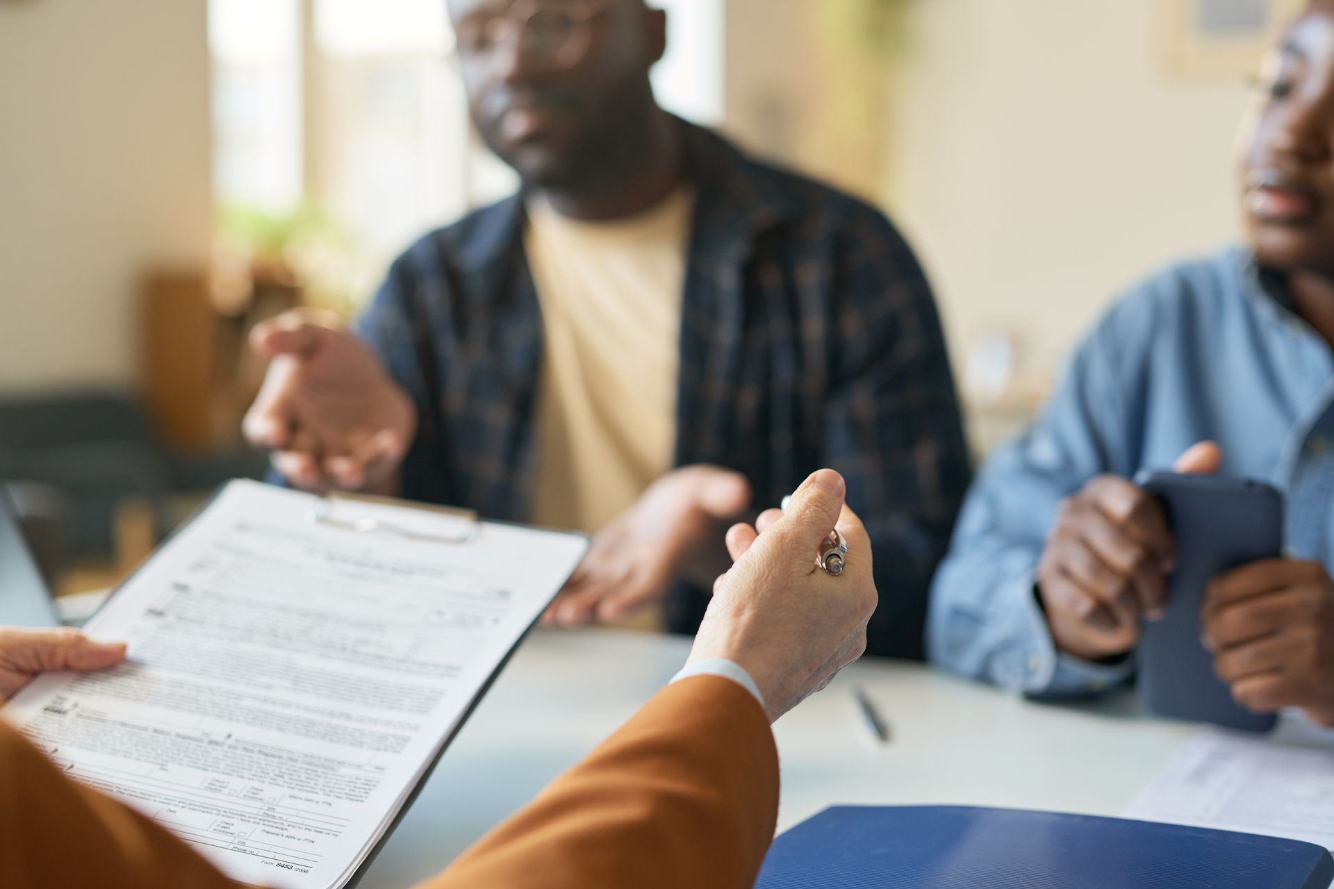 Person holding pen, presenting document to two people at table