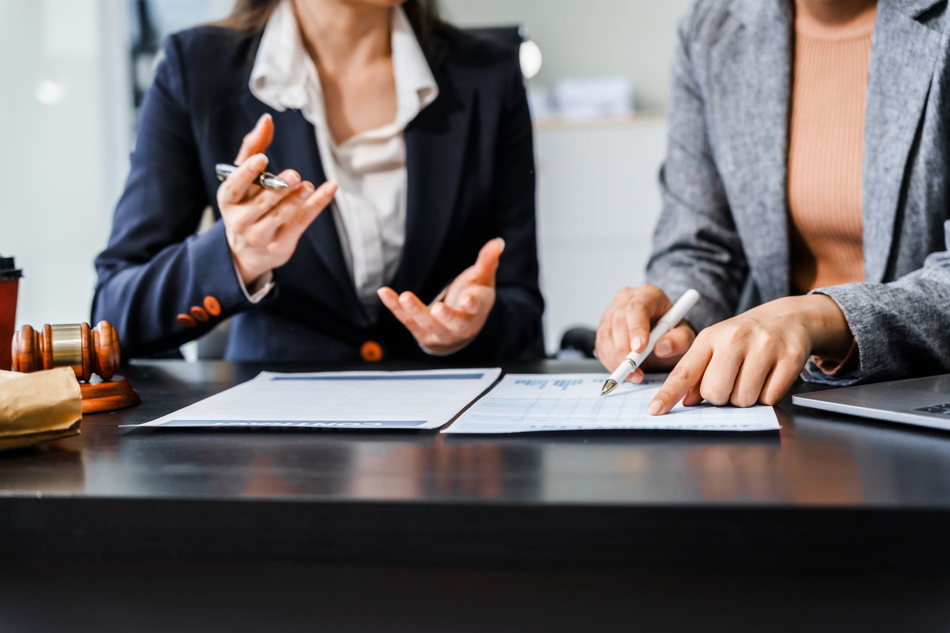 Two people in business attire review documents at a desk