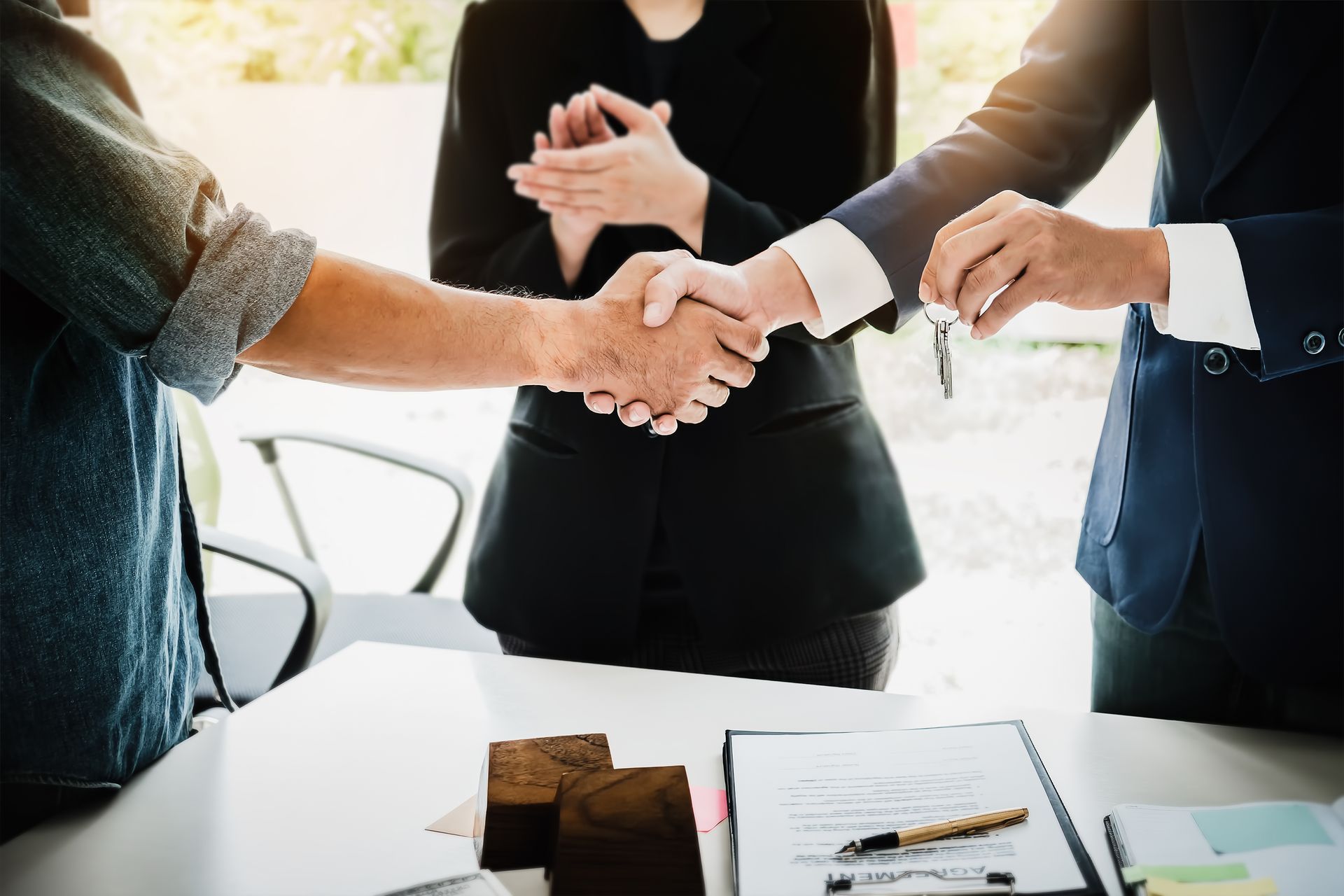 Two men shake hands over a desk