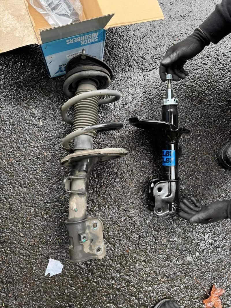 A Person Is Working on A Shock Absorber on The Ground — BEB Automotive In Berkeley, NSW