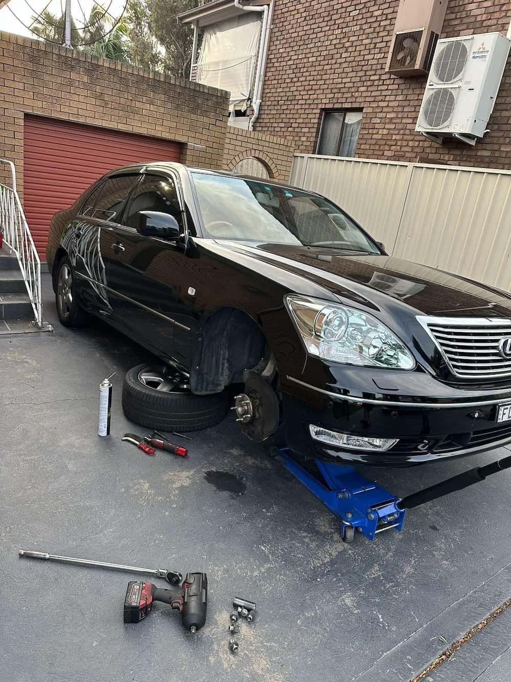 A Black Car Is Sitting on A Jack in A Driveway — BEB Automotive In Berkeley, NSW