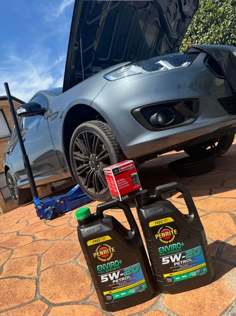 Two Bottles of Oil Are Sitting Next to A Car with The Hood Up — BEB Automotive In Berkeley, NSW