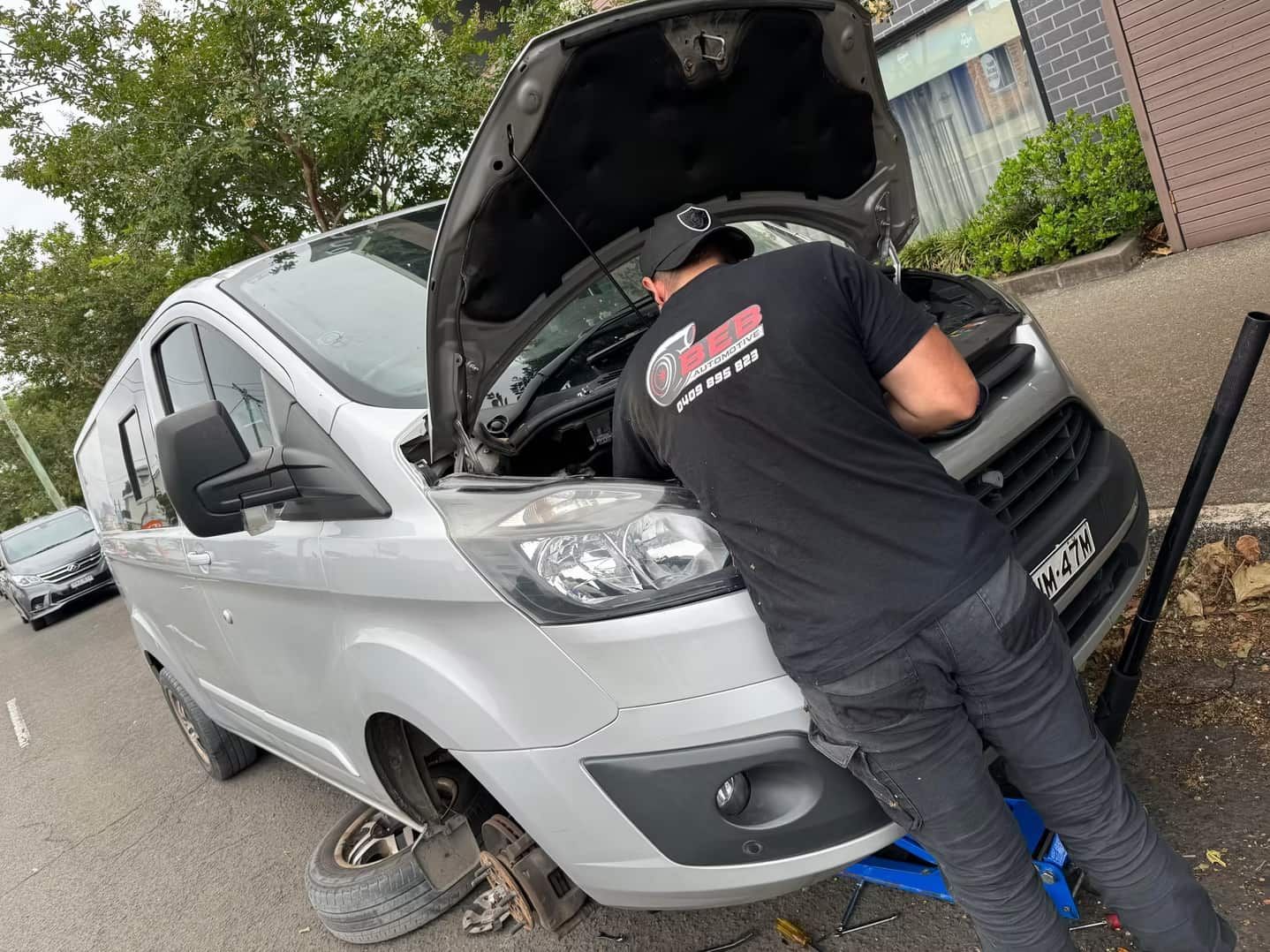 A Man Is Working on The Engine of A White Van — BEB Automotive In Berkeley, NSW