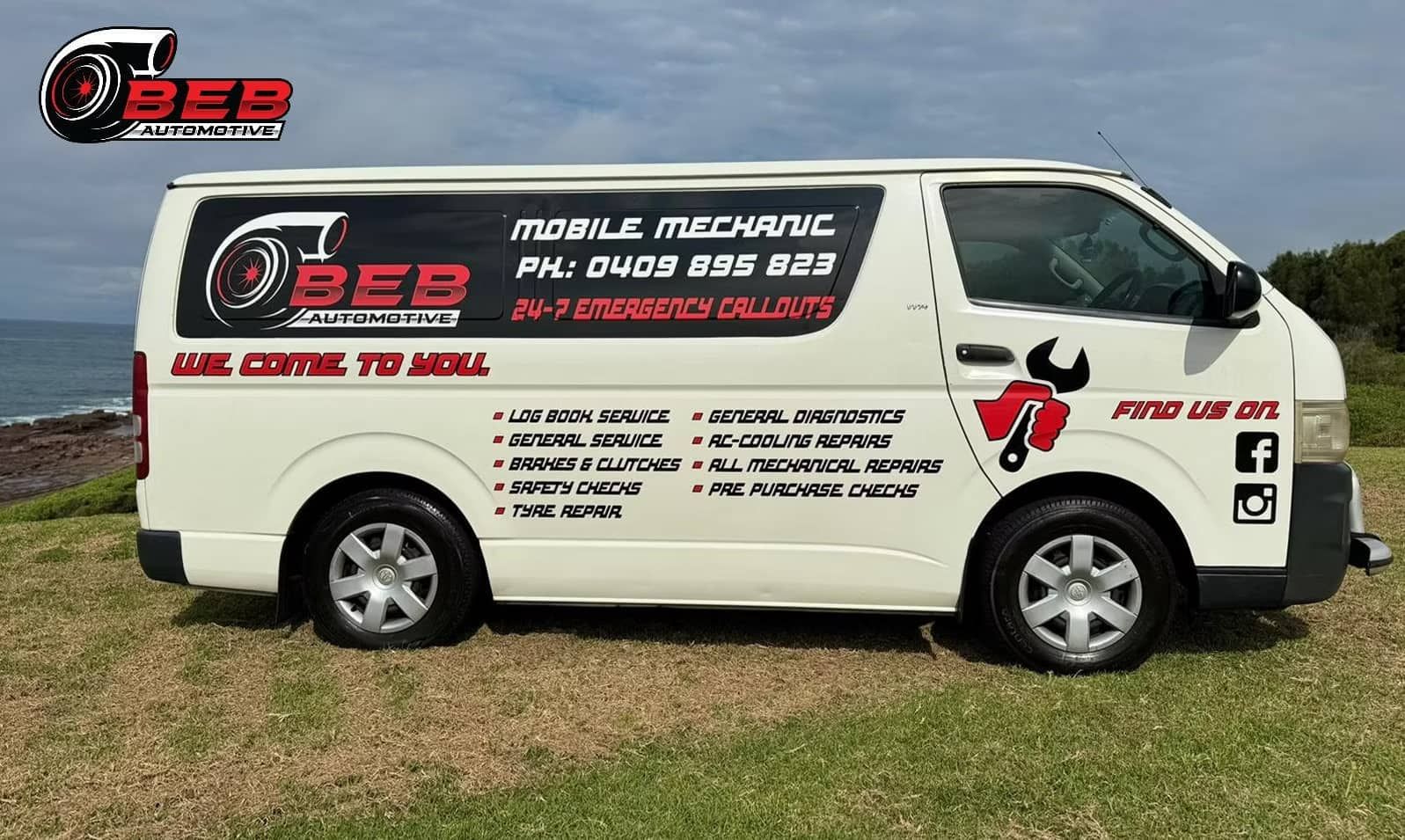 A White Van Is Parked on A Grassy Field Next to The Ocean — BEB Automotive In Berkeley, NSW