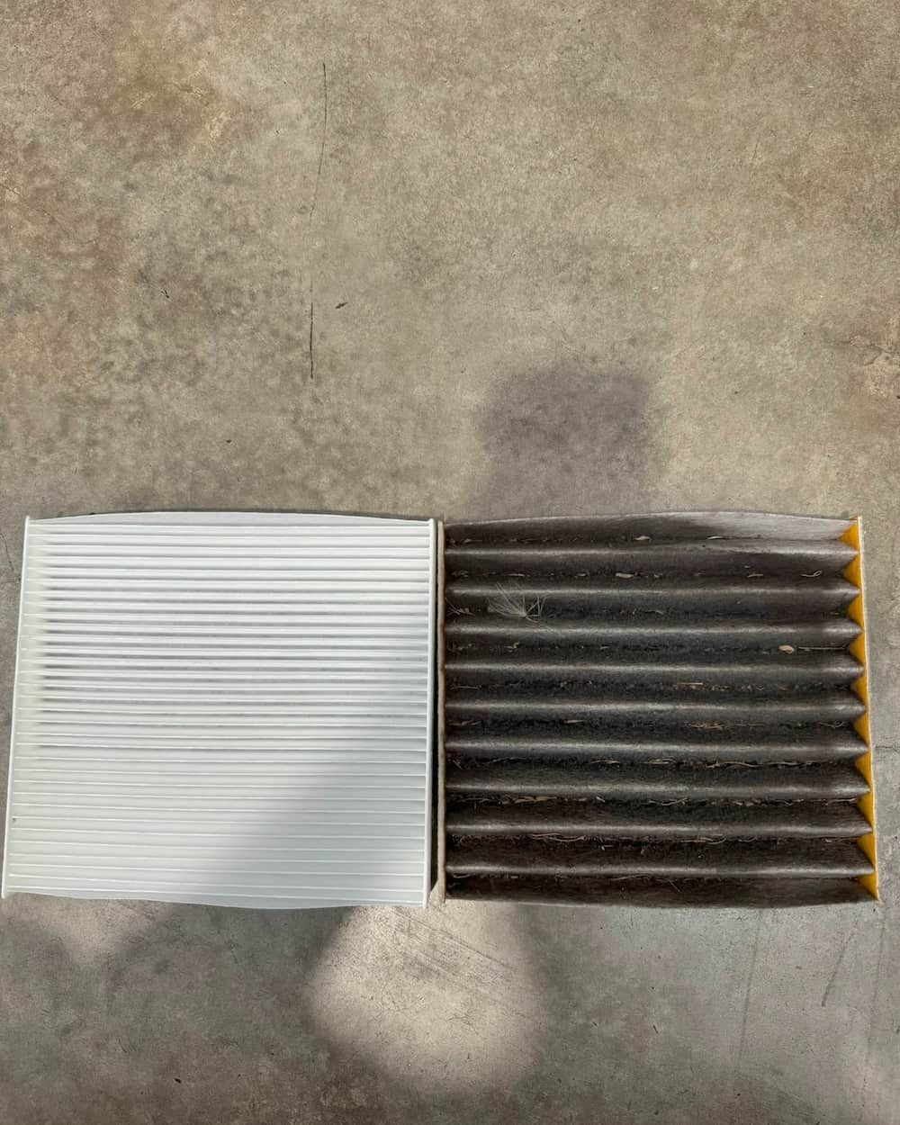 A Clean Air Filter and A Dirty Air Filter Are Sitting Next to Each Other on A Concrete Surface — BEB Automotive In Shellharbour, NSW