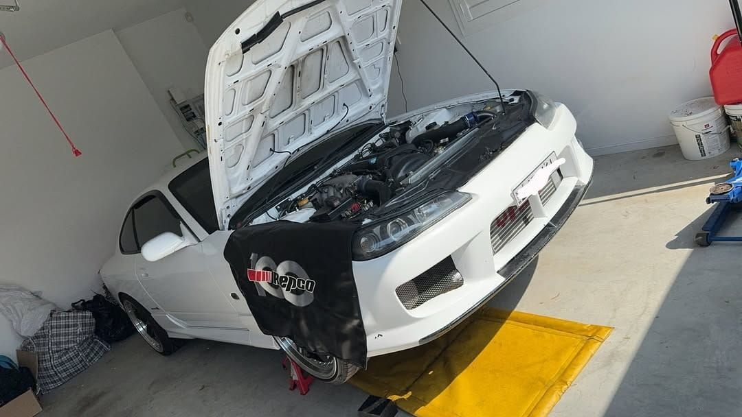 A White Car with The Hood Open Is Sitting on A Lift in A Garage — BEB Automotive In Nowra, NSW