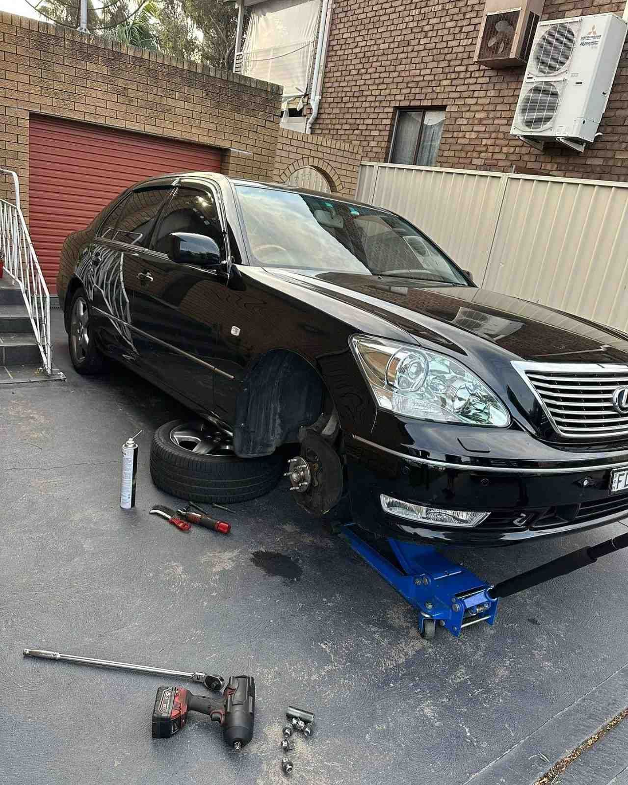 A Car with A Flat Tire Being Repaired in A Driveway — BEB Automotive In Bankstown, NSW