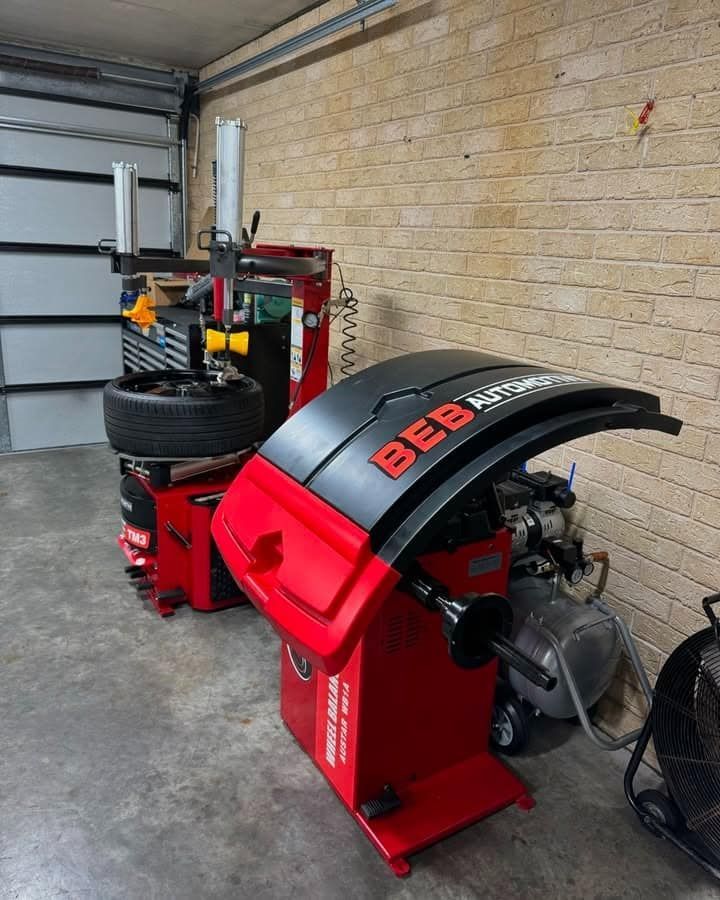 A Tire Balancing Machine Is Sitting in A Garage Next to A Brick Wall — BEB Automotive In Albion Park, NSW