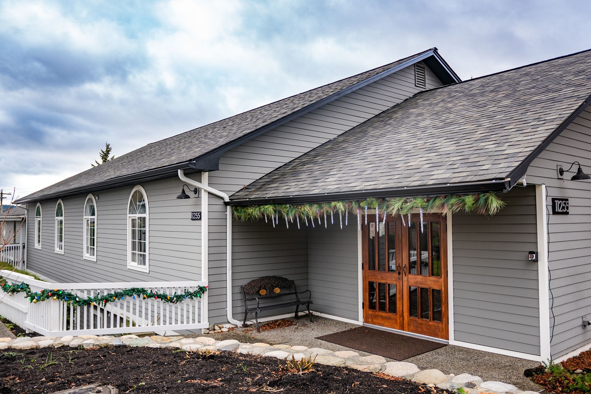 A large gray house with a black roof and a wooden door.