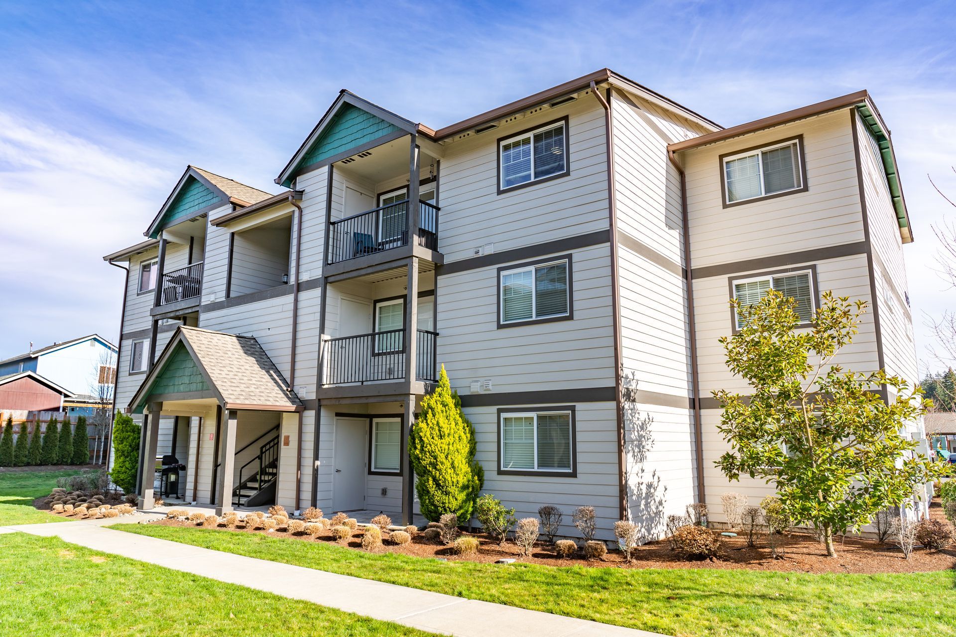 A large apartment building with a lush green lawn in front of it.