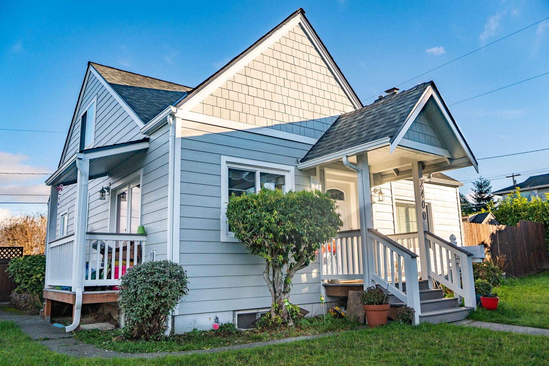 A small white house with a porch and stairs in front of it.