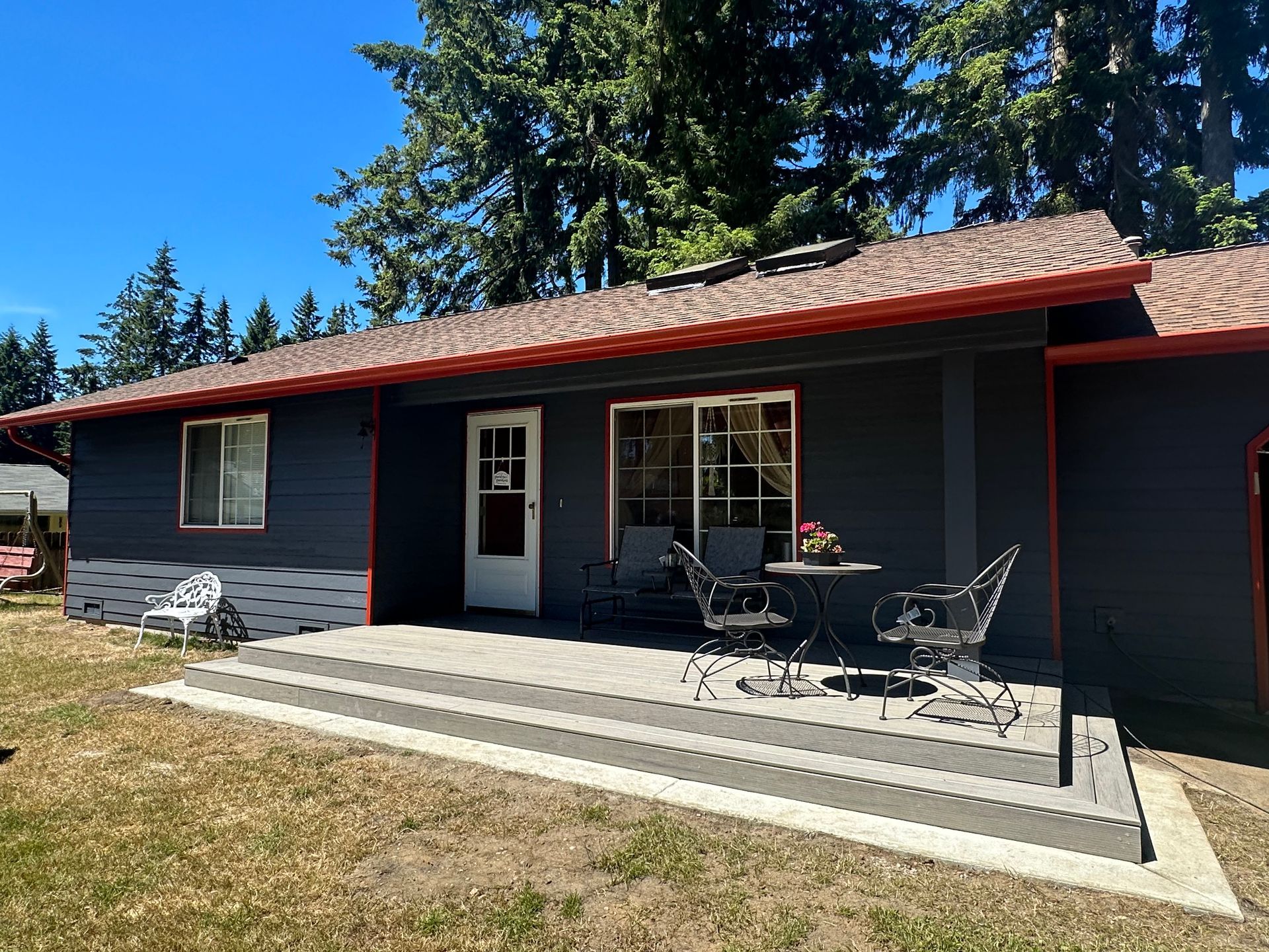 A black house with a patio and a table and chairs in front of it.