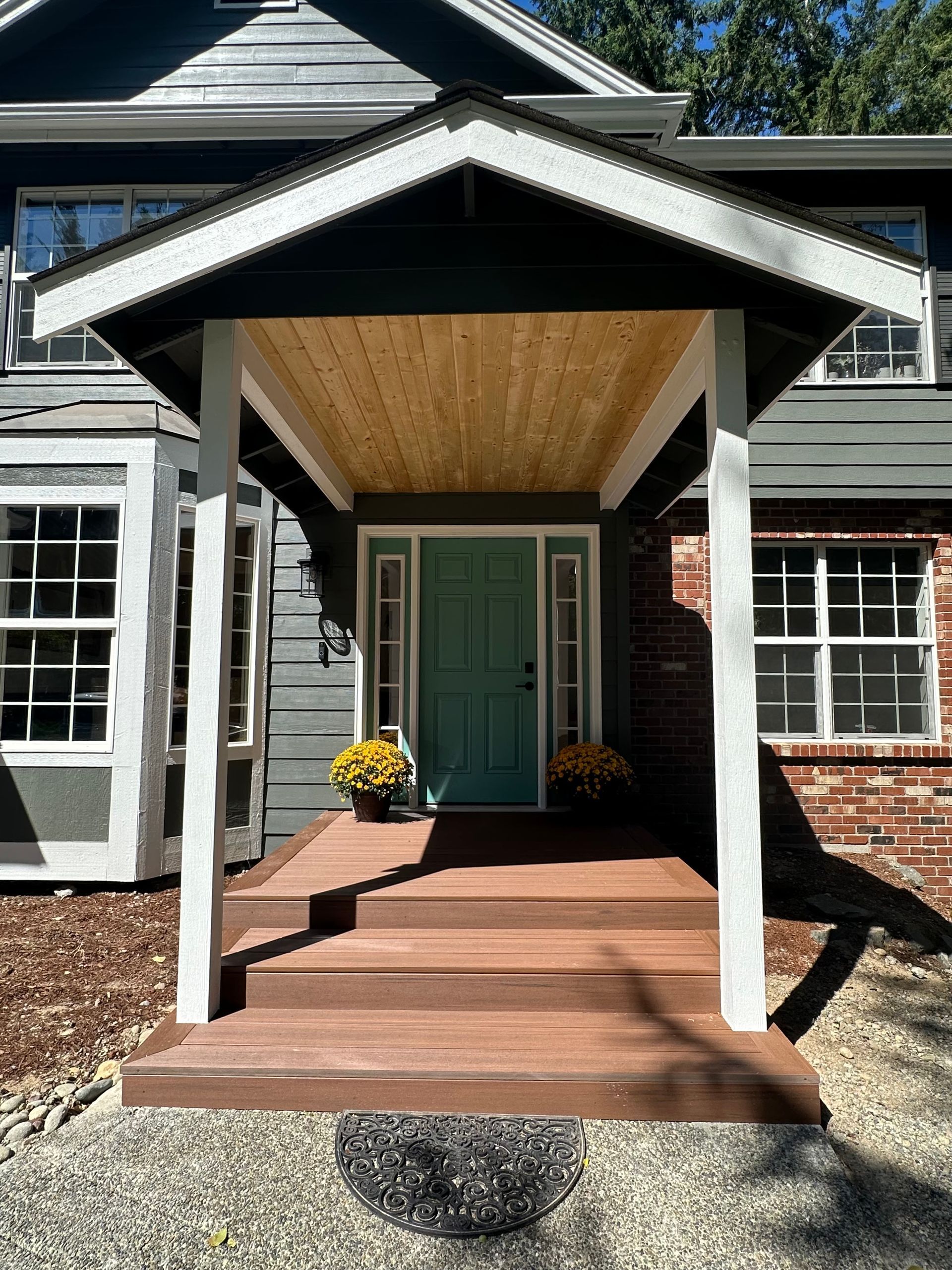 The front porch of a house with a blue door and a wooden deck.
