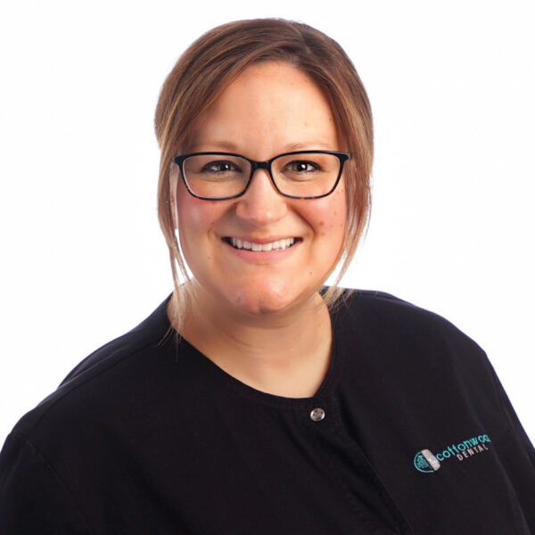 Woman wearing glasses and a black scrub top with the logo 