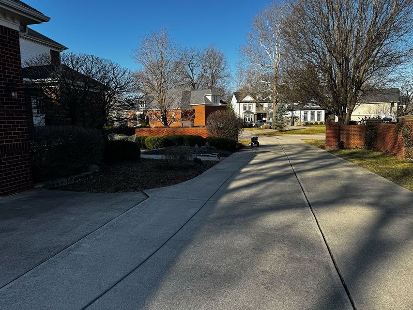 A concrete driveway leading to a house in a residential neighborhood.