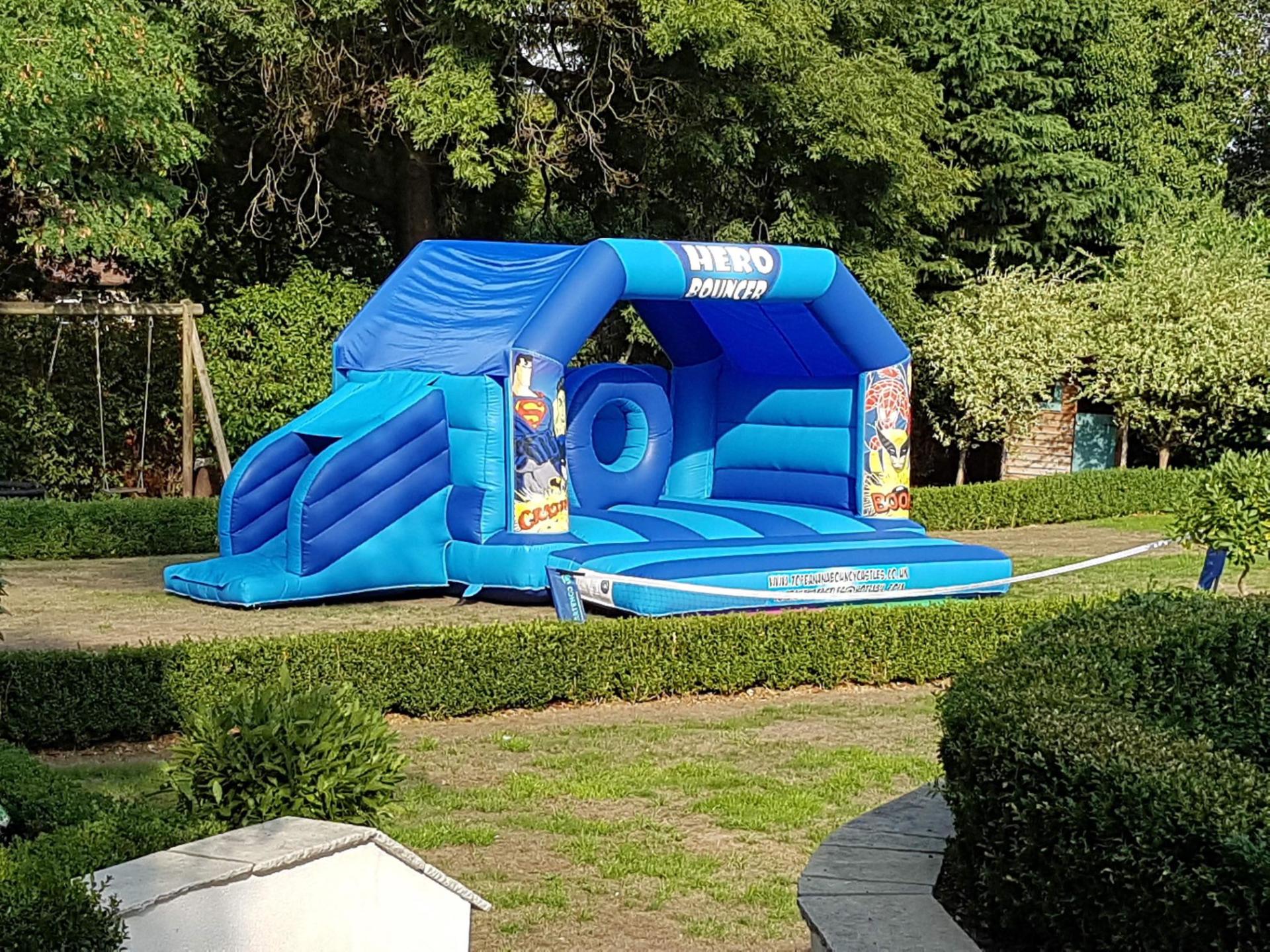 super hero slide combo bouncy castle in large garden