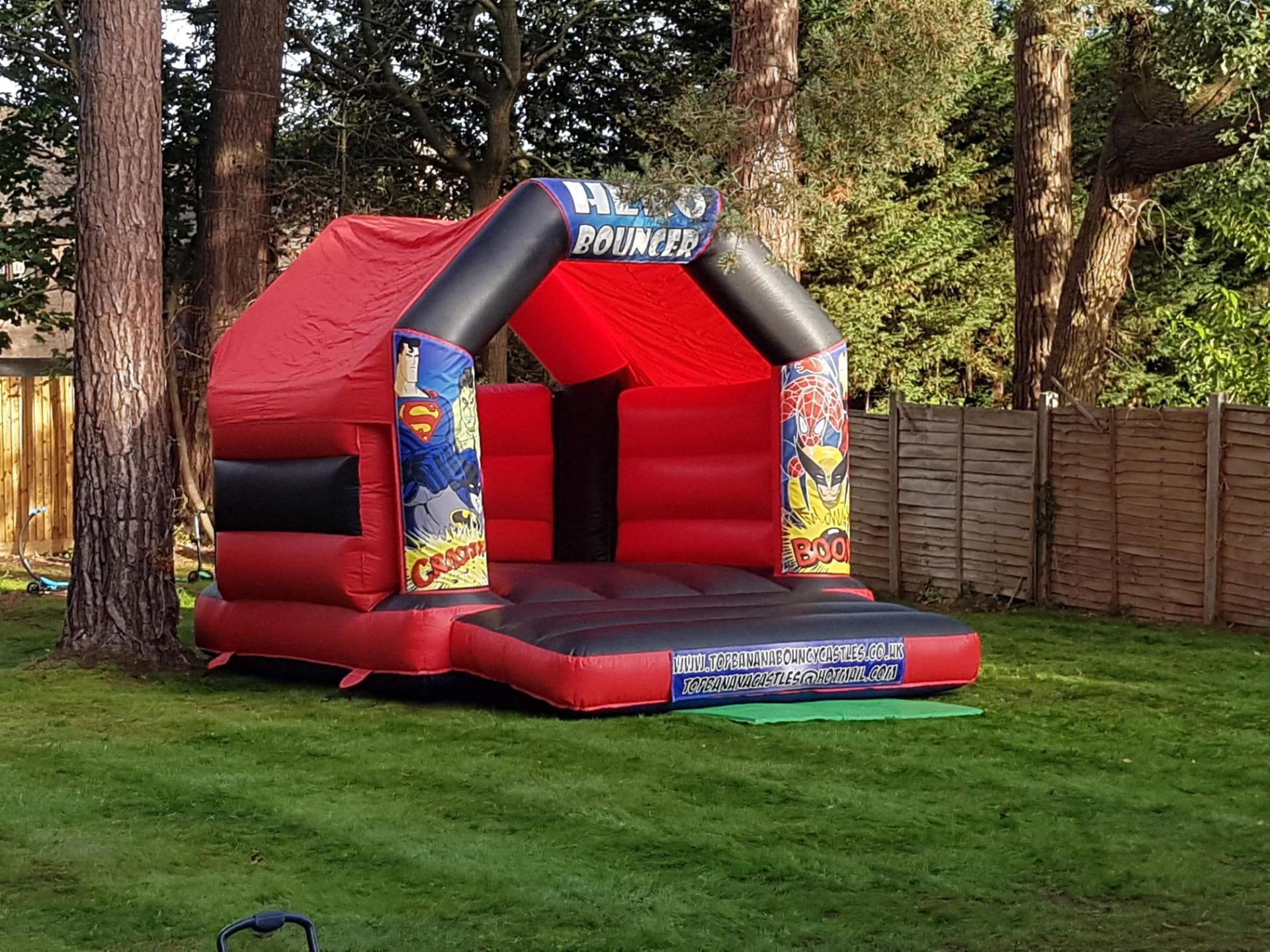red and black super hero small bouncy castle in a garden