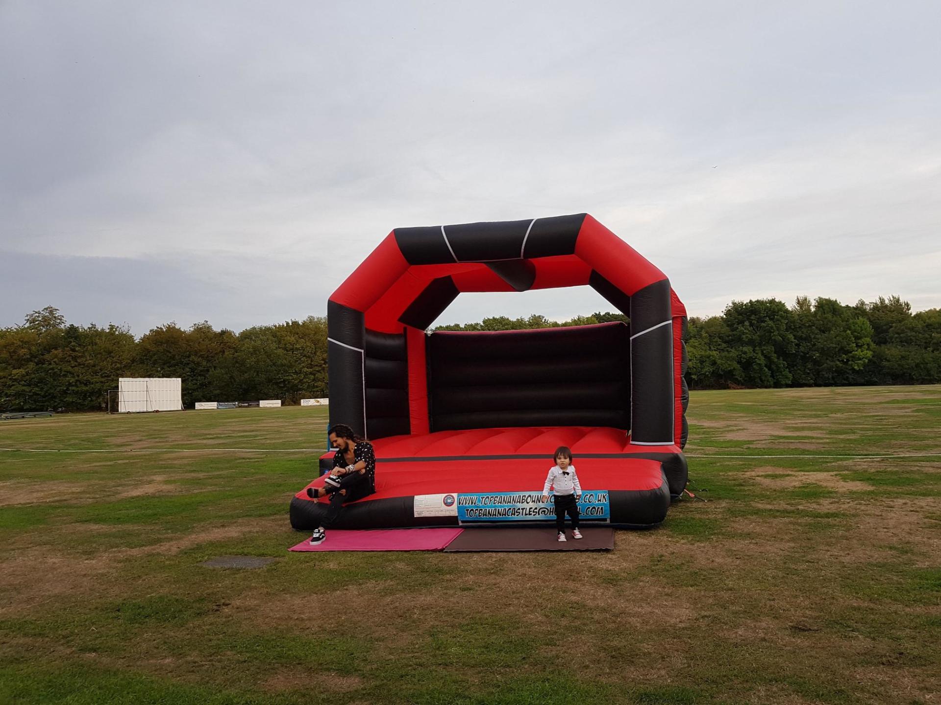 large red and black bouncy castle in a field