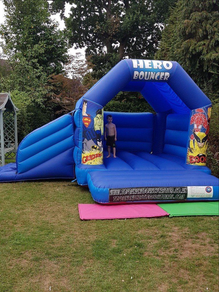 super hero theme slide combo bouncy castle in a garden