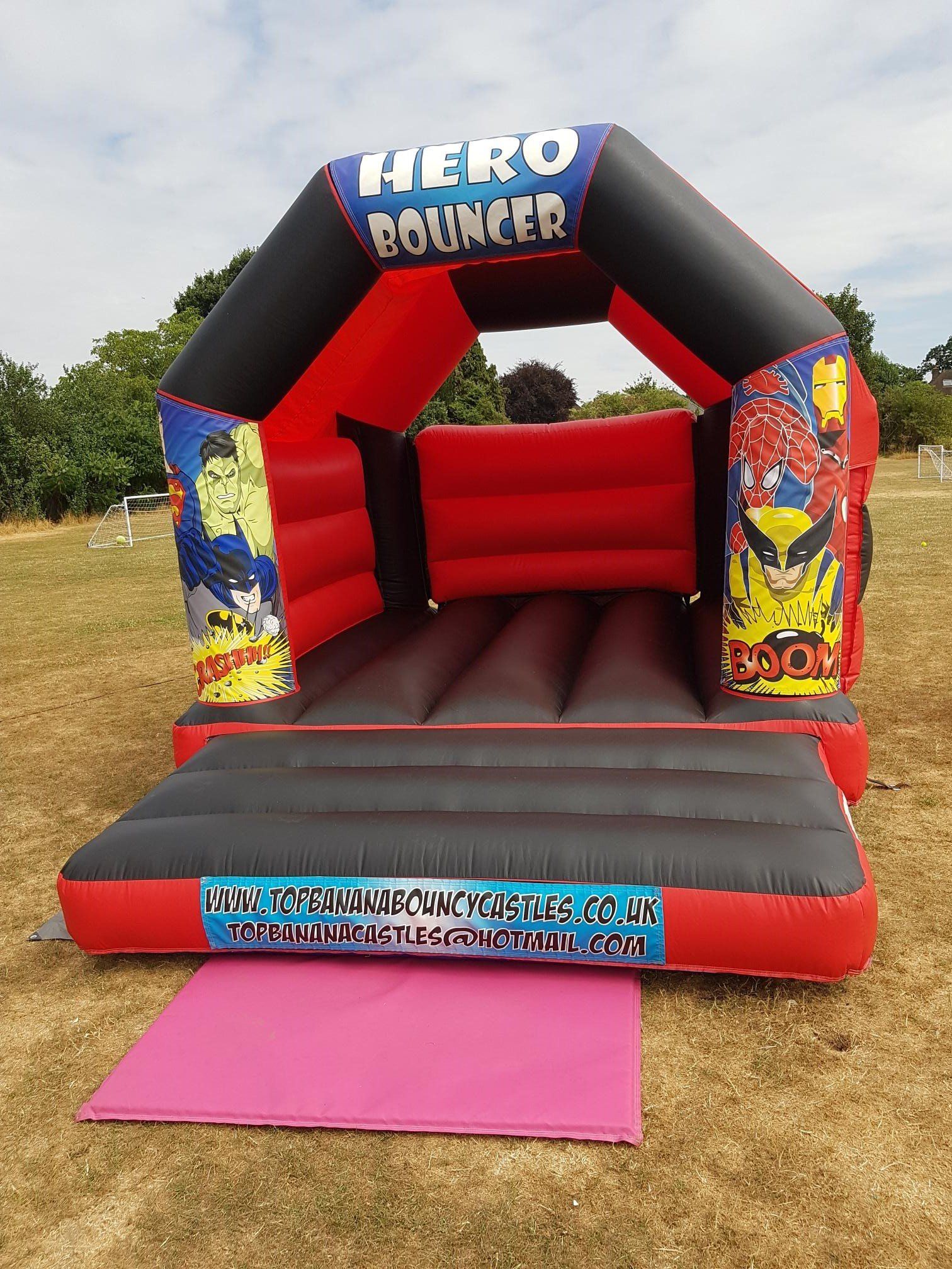 red and black super hero small bouncy castle in a field