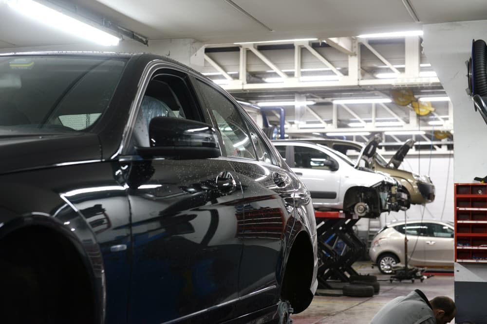 A Black Car Is Parked in A Garage with Other Cars — Palmerston Auto Clinic in Yarrawonga, NT