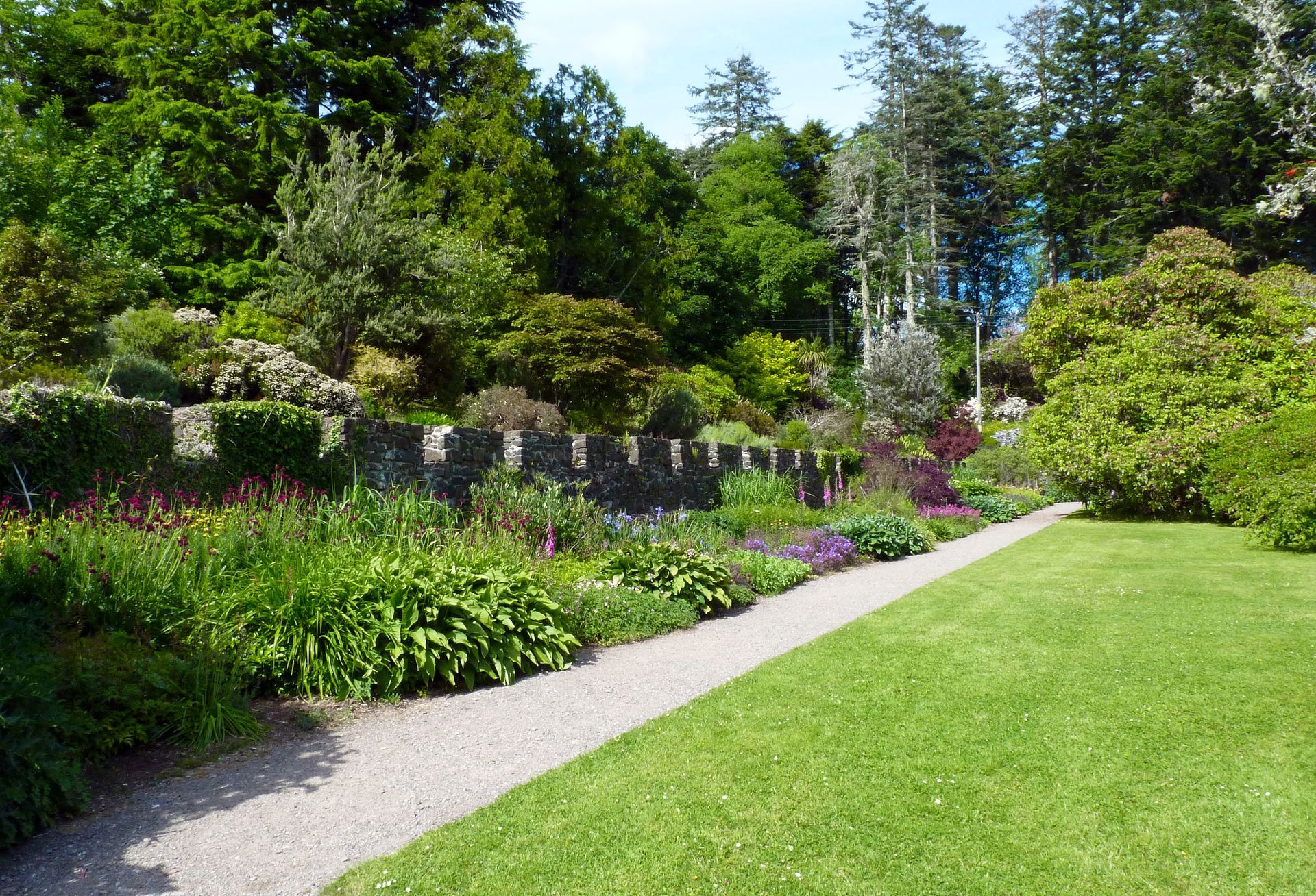 Scenic path leading from a lush green lawn to a vibrant garden bursting with colorful plants.