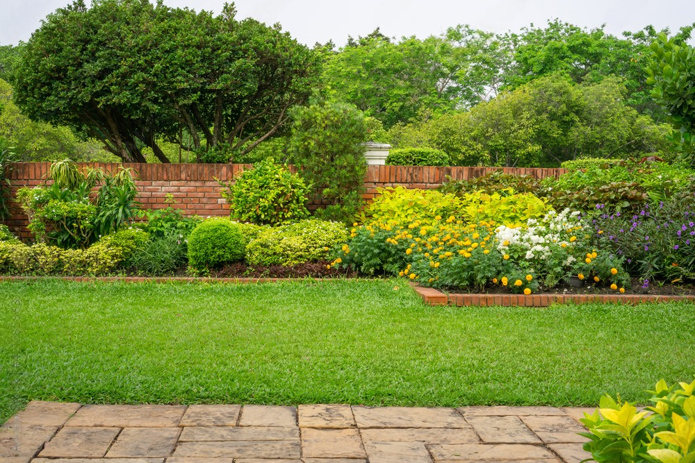 a garden with a brick wall and lots of flowers