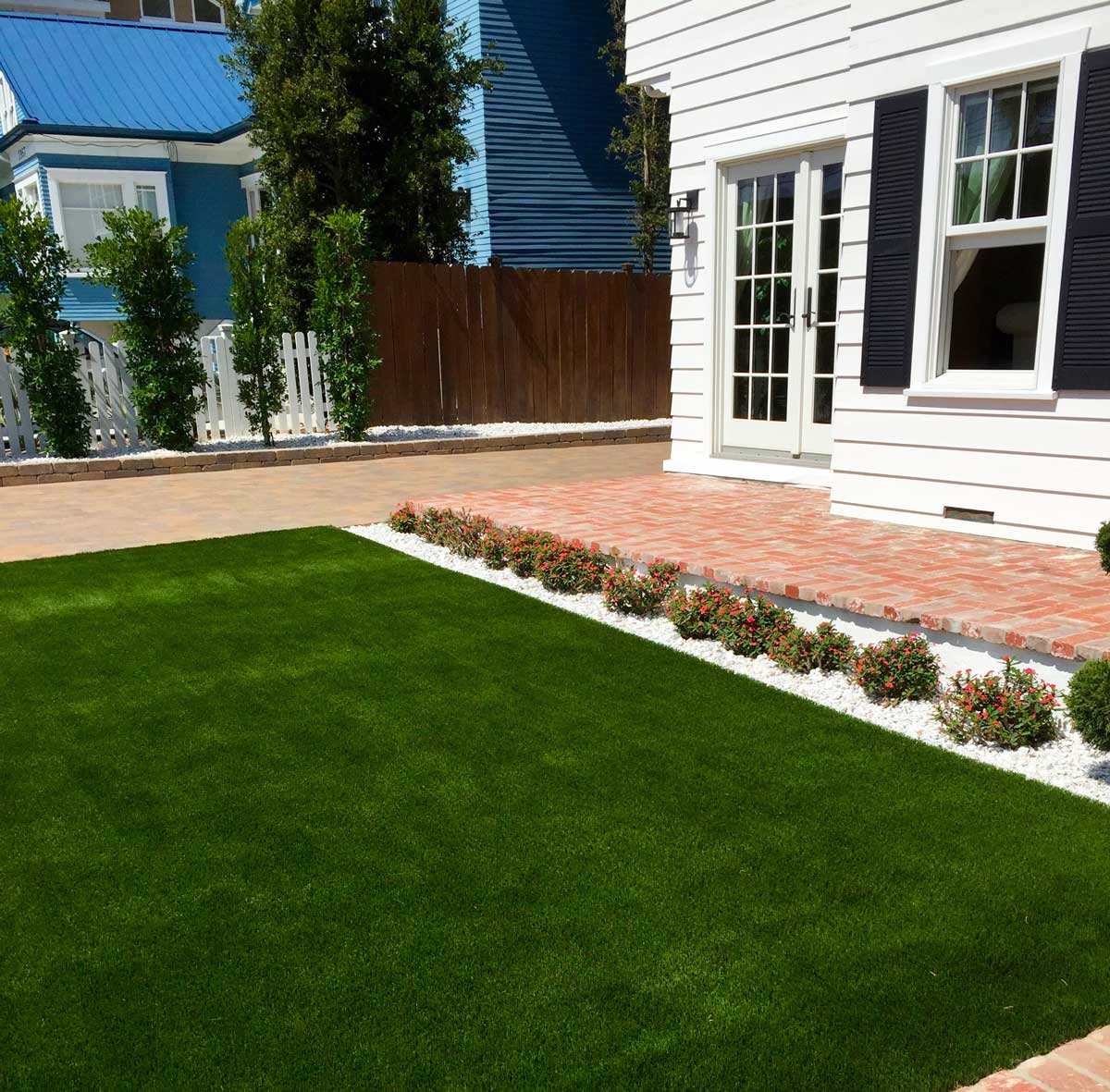 White House with a lush green lawn and staircase adorned with vibrant plants.