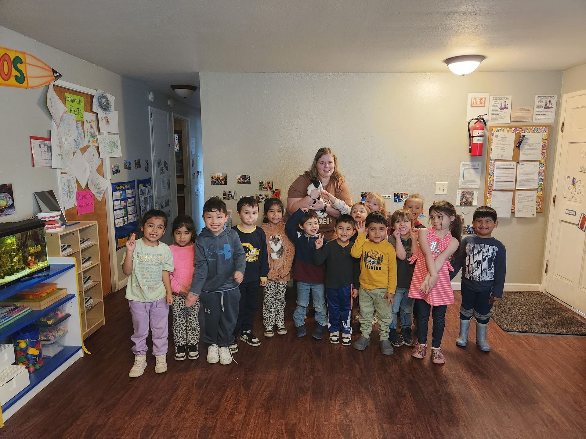A group of children are posing for a picture with their teacher in a classroom.