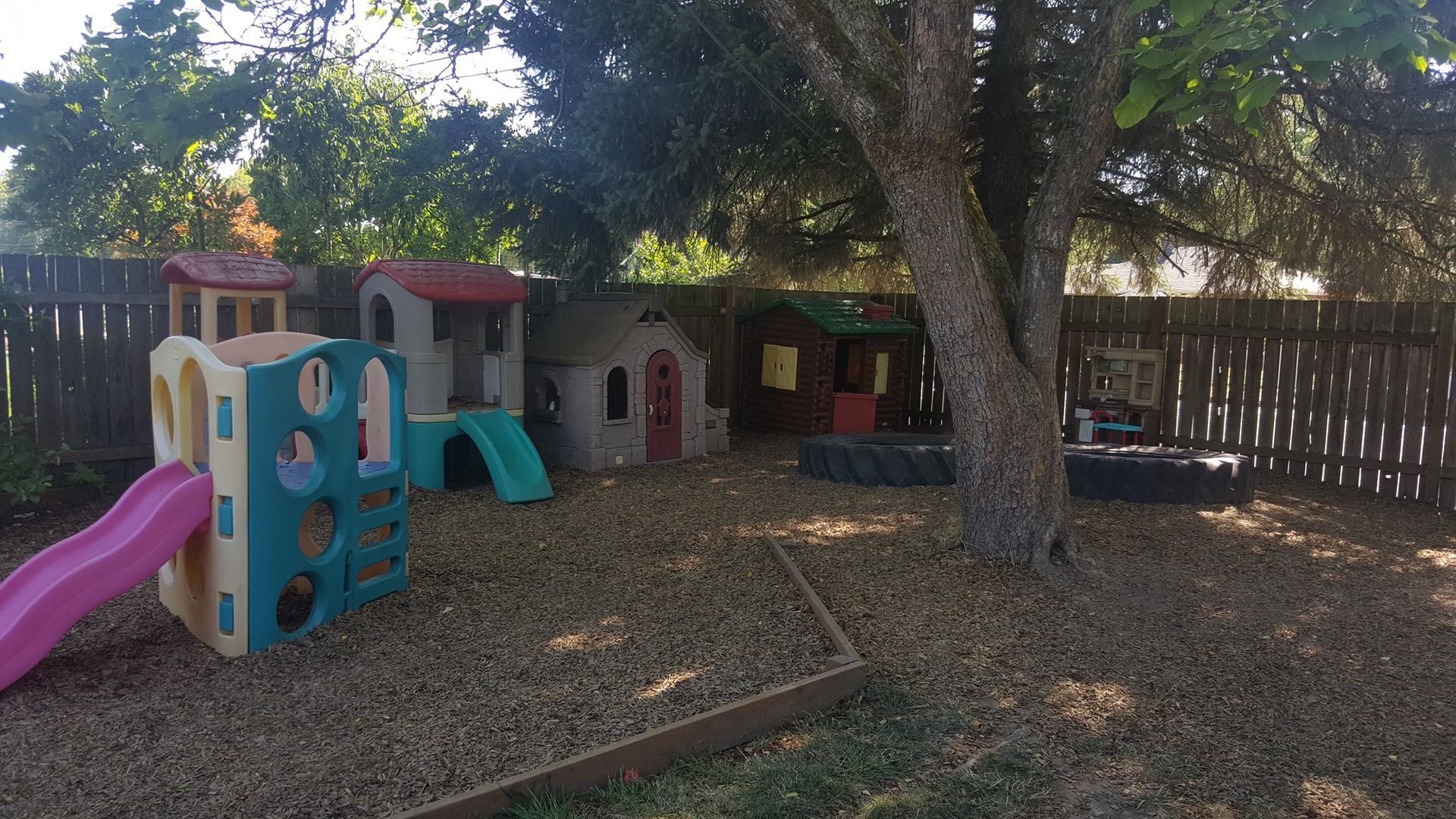 A playground with a slide , climbing wall , and playhouse.