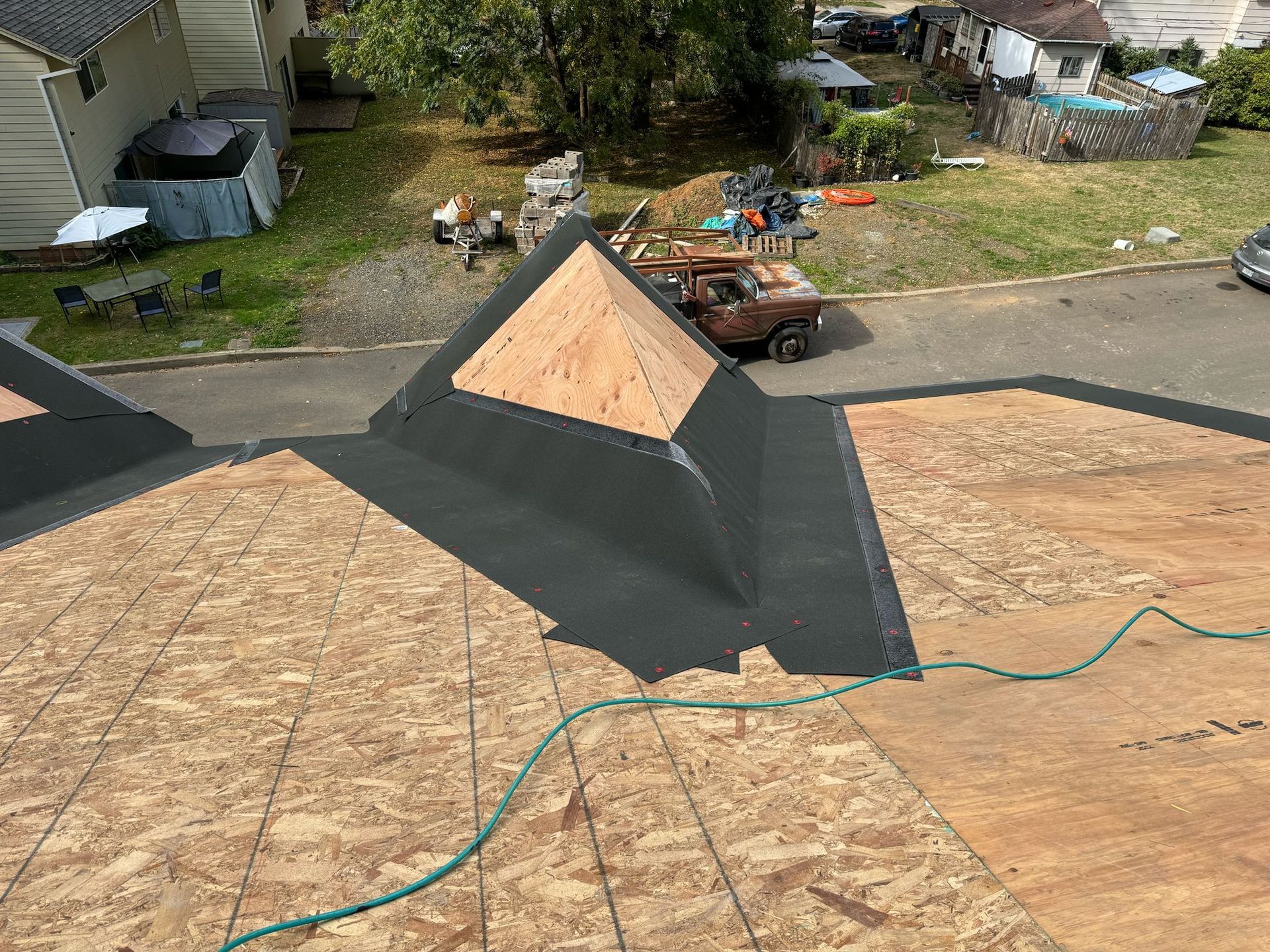 Newly constructed roof with exposed plywood and black roofing material.