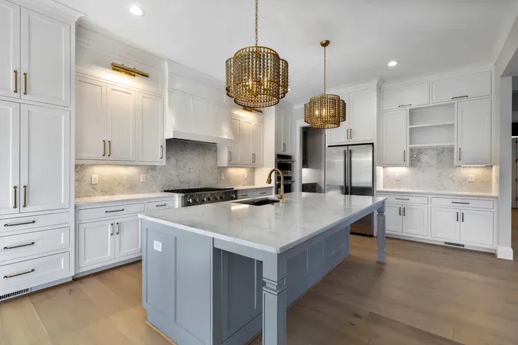 Bright modern kitchen with white cabinets, large island, and brass pendant lights