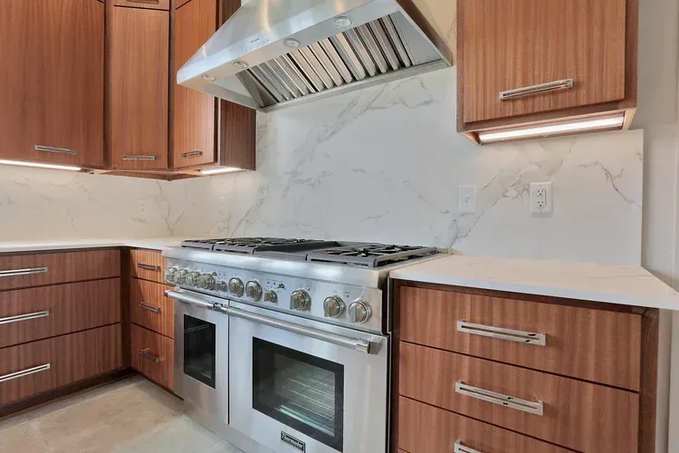 Modern kitchen with stainless steel range, range hood, and wood cabinets