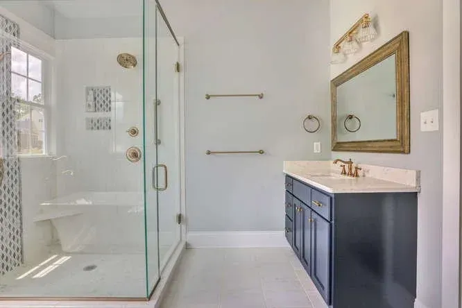 Bright bathroom with glass shower, navy vanity, white walls, and large mirror