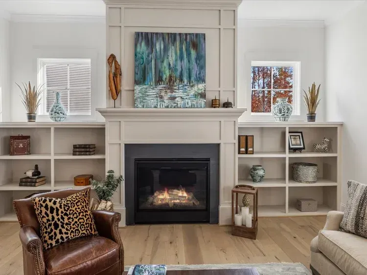 Bright living room with a fireplace, built-in shelves, and blue abstract art above the mantel