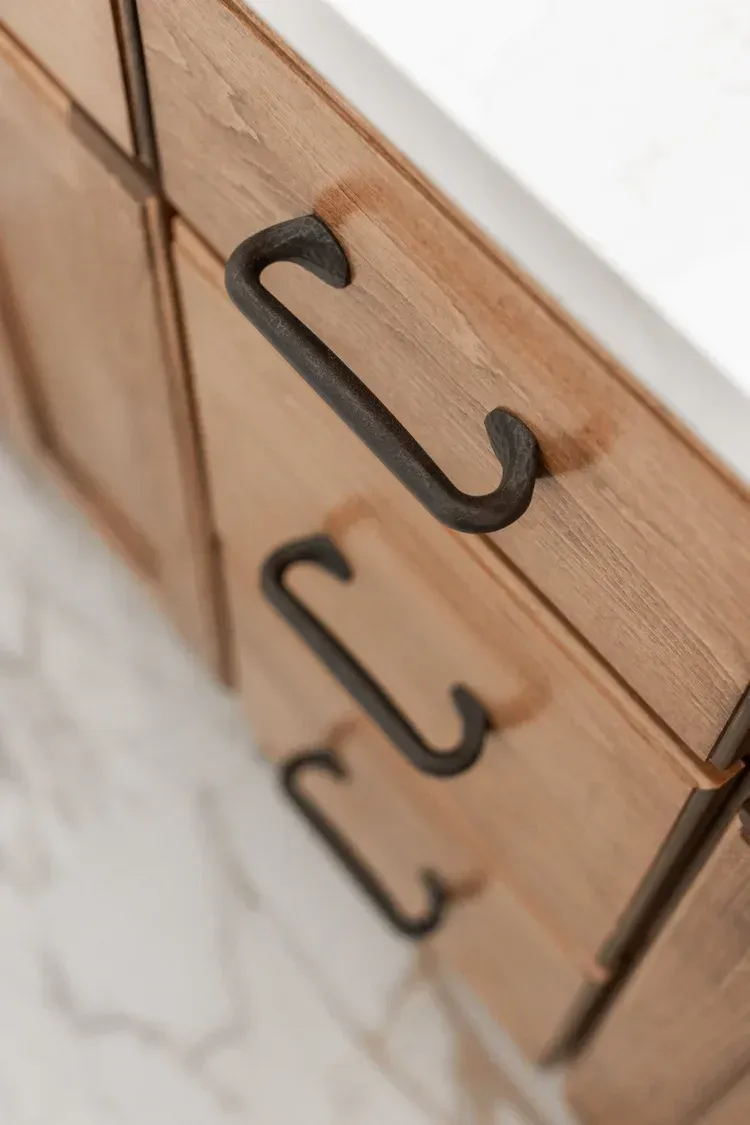 Wooden cabinet drawers with black metal pull handles, viewed at an angle