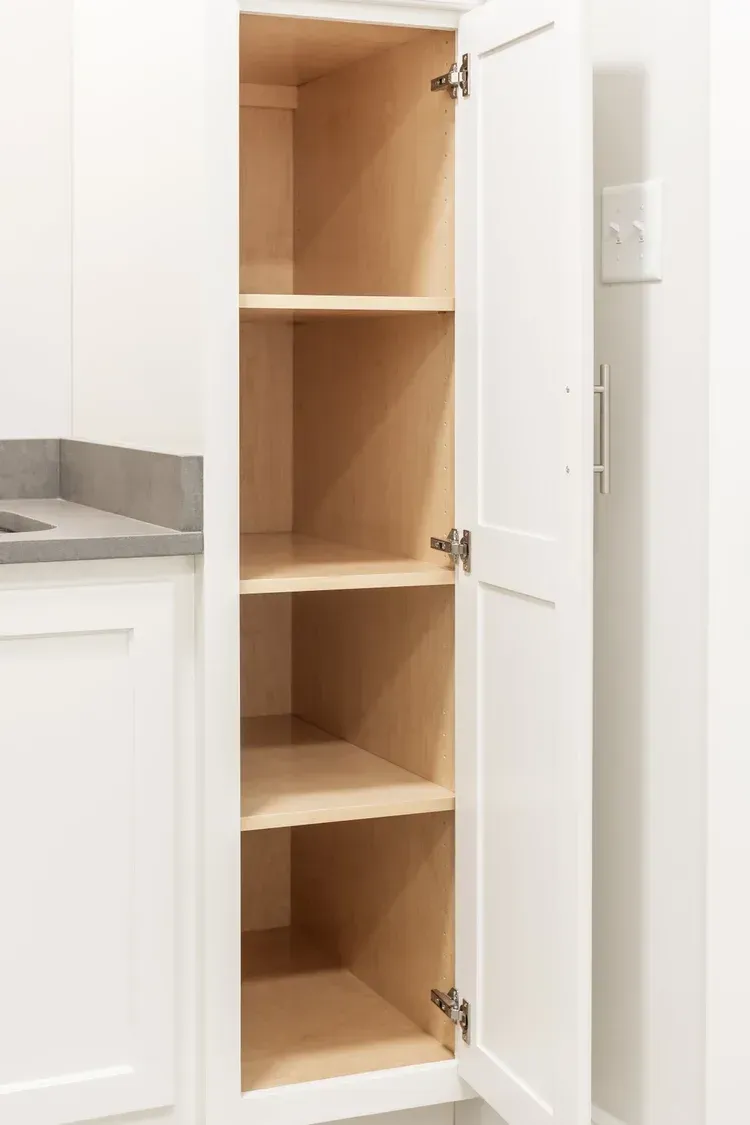 Open white cabinet with empty wooden shelves in a kitchen cabinet niche