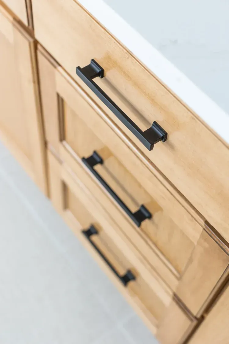 Light wood dresser with black drawer pulls, viewed at an angle