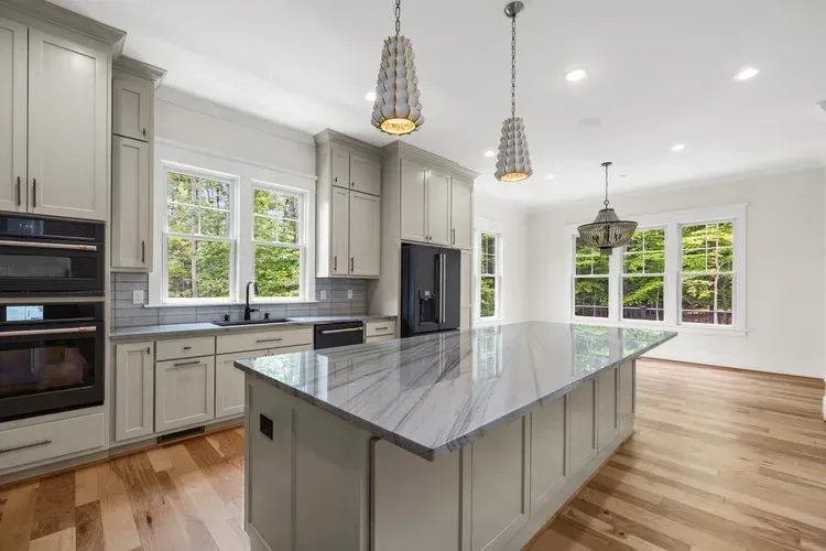 Bright modern kitchen with gray cabinets, large island, pendant lights, and wood floors