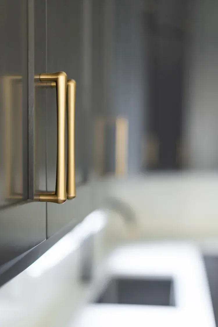 Gold cabinet handle on dark gray cabinetry in a modern kitchen