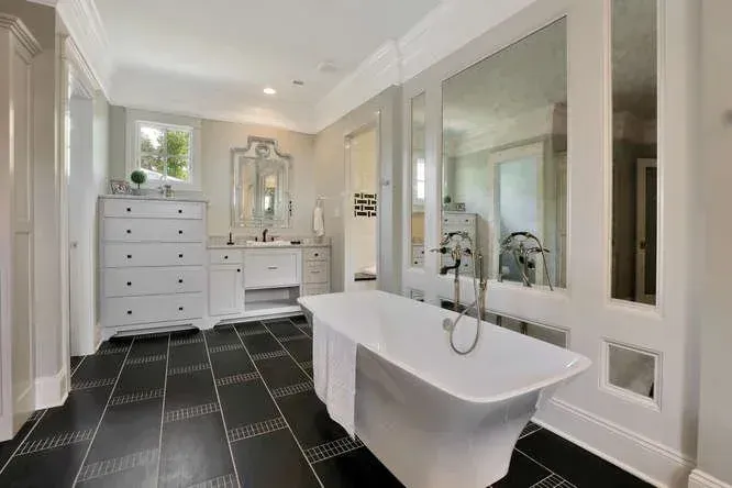 Bright modern bathroom with freestanding tub, double vanity, and black tiled floor