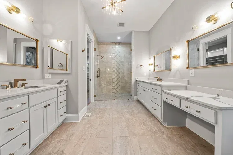 Bright modern bathroom with double vanity, large mirrors, and glass shower in a white-and-beige interior
