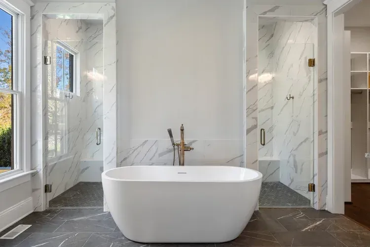 Modern bathroom with a freestanding tub, marble showers, and dark tiled floor