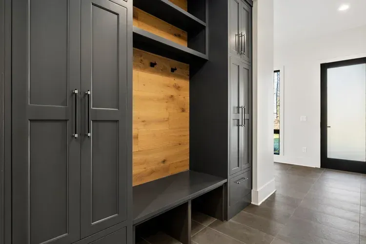 Built-in charcoal cabinets with wood cubby in a modern entryway with dark tile floor