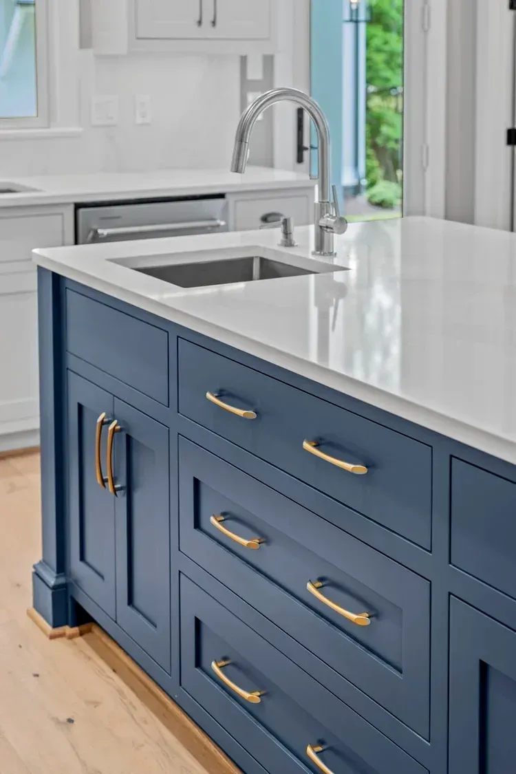 Blue kitchen island with white countertop and sink in a bright modern kitchen