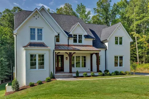 Large white two-story house with a front porch, gabled roof, and green lawn